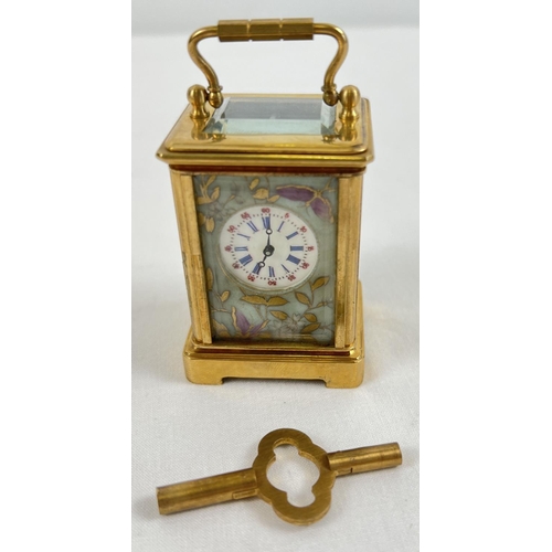 1206 - A miniature brass cased carriage clock with hand painted porcelain panels. Bevel edged glass, gilt d... 