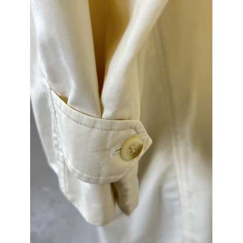 1331 - A cream light weight belted trench coat by Burberrys. Front button fastening with 2 front pockets. B... 