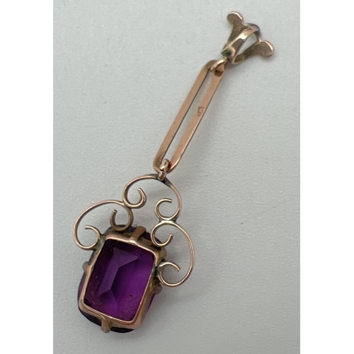 1064 - An Art Noveau 9ct rose gold drop pendant set with an emerald cut amethyst. Scroll work mount surroun... 