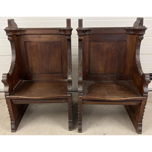 1365 - A pair of antique dark oak church sideman's pew chairs. With panelled backs and shaped arms. Each ap... 