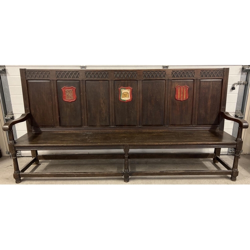 1366 - An antique dark wood high back settle bench with painted crest detail. Panelled back with carved Got... 