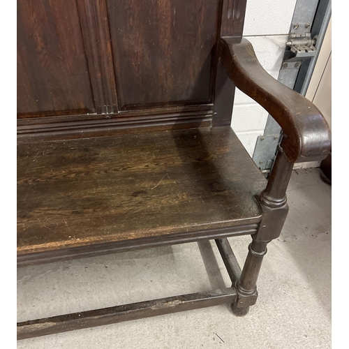 1366 - An antique dark wood high back settle bench with painted crest detail. Panelled back with carved Got... 