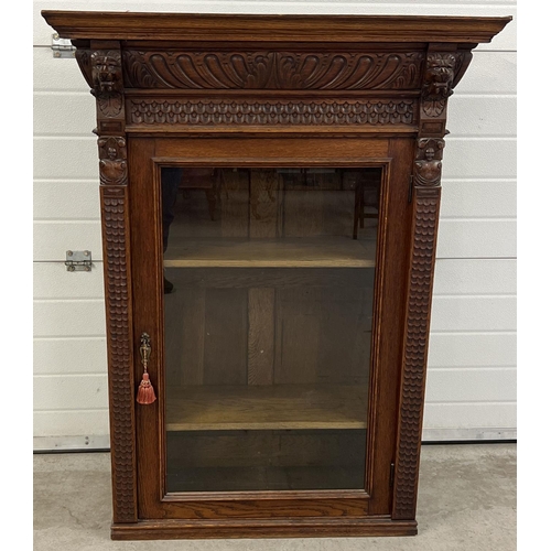 1367 - An antique dark wood wall hanging display cupboard with highly carved detail. With lion head finials... 