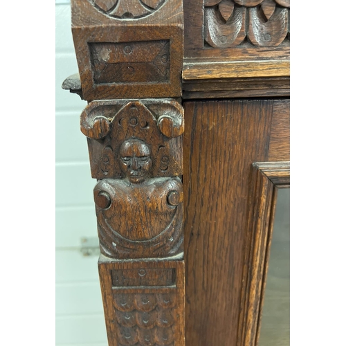 1367 - An antique dark wood wall hanging display cupboard with highly carved detail. With lion head finials... 