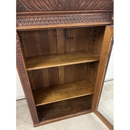 1367 - An antique dark wood wall hanging display cupboard with highly carved detail. With lion head finials... 