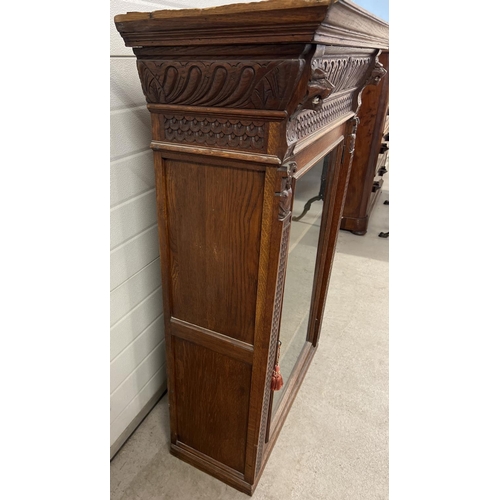 1367 - An antique dark wood wall hanging display cupboard with highly carved detail. With lion head finials... 