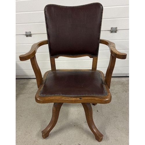 1373 - A vintage dark oak captains chair with 4 legged swivel base. Brown faux leather upholstery with stud... 