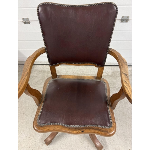 1373 - A vintage dark oak captains chair with 4 legged swivel base. Brown faux leather upholstery with stud... 