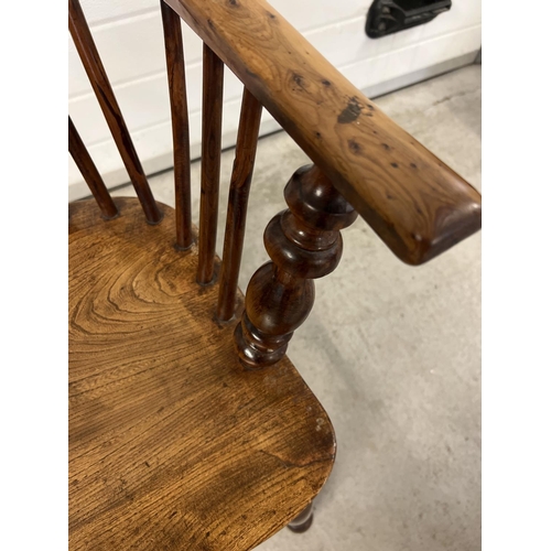 1374 - An antique spindle backed yew wood Windsor chair with curved stretcher and turned supports.