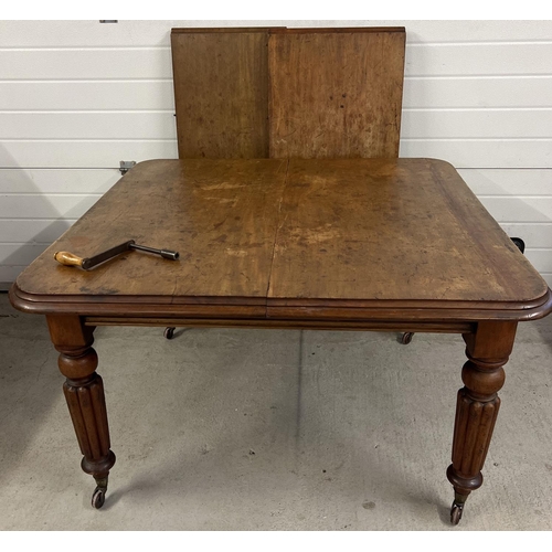 1376 - An antique mahogany wind out dining table with turned legs and castor feet. Complete with winding ha... 