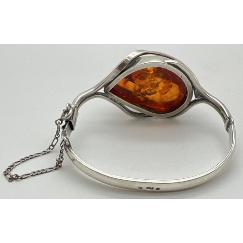 1005 - A modern design silver and Baltic amber bangle style bracelet with safety chain. Large central piece... 