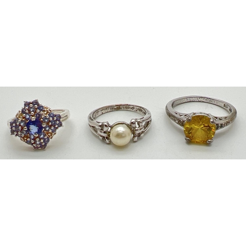 1073 - 3 gem set silver dress rings. A central pearl ring with bow detail to shoulders; a clear stone and t... 