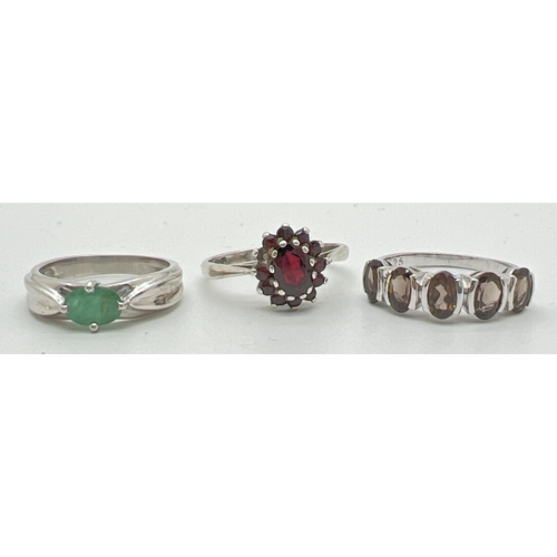 1075 - 3 silver dress rings. To include a garnet set cluster style ring and a smoked quartz set half eterni... 