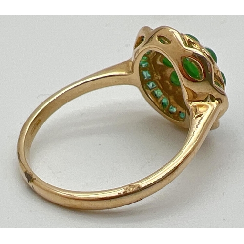 1009 - A 9ct gold emerald and jade dress ring in a fluted edge flower design by Luke Stockley, London. Set ... 