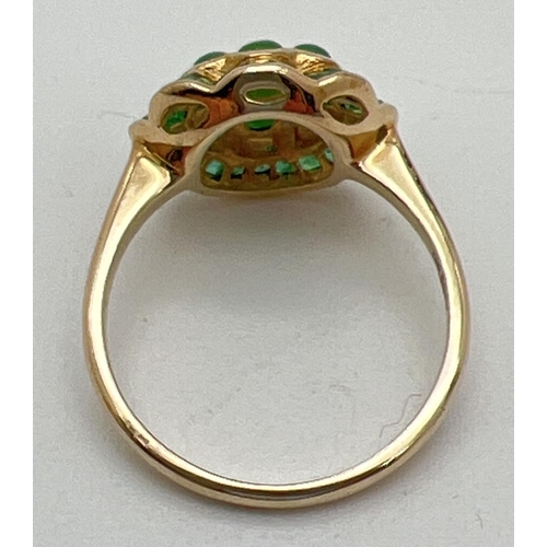 1009 - A 9ct gold emerald and jade dress ring in a fluted edge flower design by Luke Stockley, London. Set ... 