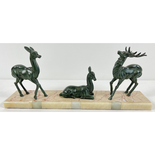 1291 - A French Art Deco marble & onyx based mantel figurine of 3 spelter deer. A seated deer flanked by a ... 