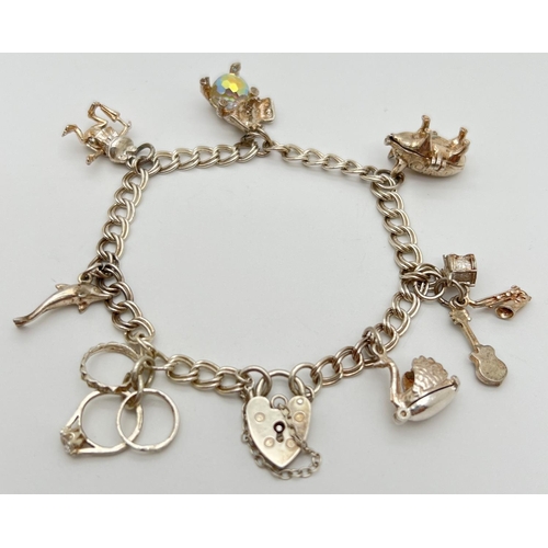 1093 - A vintage double belcher chain charm bracelet with padlock, safety chain & 7 charms. Silver marks to... 