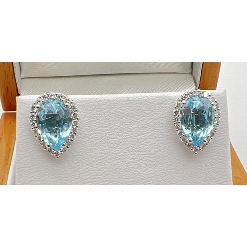 1100 - A pair of 18ct white gold blue topaz and diamond stud style earrings by Luke Stockley, London. Each ... 