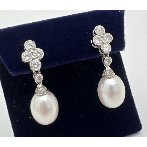 1103 - A pair of Luke Stockley 18ct white gold diamond and pearl drop style earrings. Each earring set with... 