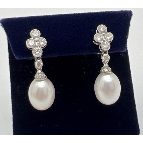 1103 - A pair of Luke Stockley 18ct white gold diamond and pearl drop style earrings. Each earring set with... 