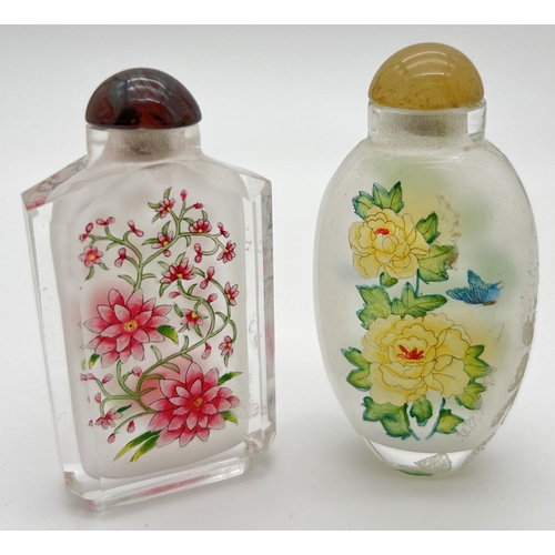 1244 - 2 vintage oriental interior painted glass snuff bottles of floral design. With coloured glass stoppe... 