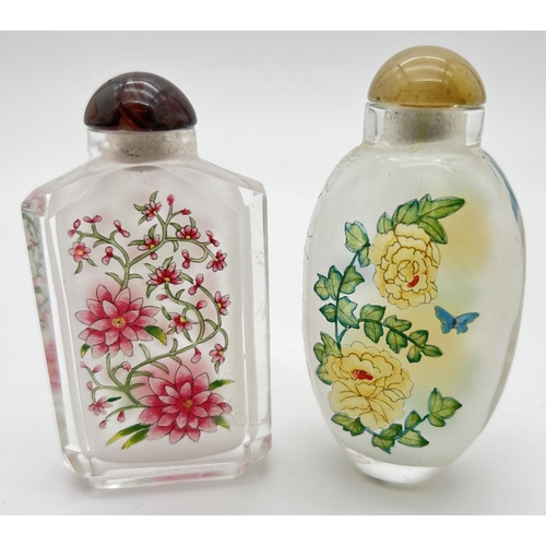 1244 - 2 vintage oriental interior painted glass snuff bottles of floral design. With coloured glass stoppe... 