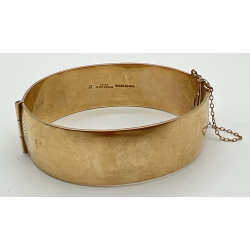 1115 - A vintage 9ct rolled gold bangle with safety chain and floral engraving to front. Makers mark and go... 