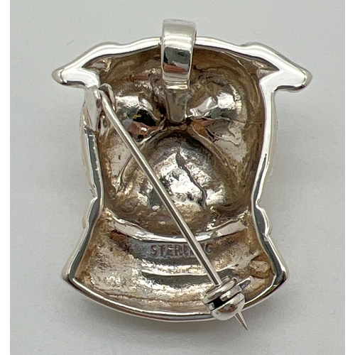 1120 - A sterling silver brooch/pendant in the shape of a dogs head with yellow glass eyes. Reverse with pi... 