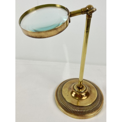 1299 - A table top adjustable brass magnifying glass, on a stand with circular base. Tallest height approx.... 