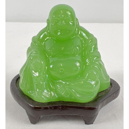 1299 - A small carved green jade sitting Buddha figure on a small wooden stand. Figure approx. 5.5cm tall.