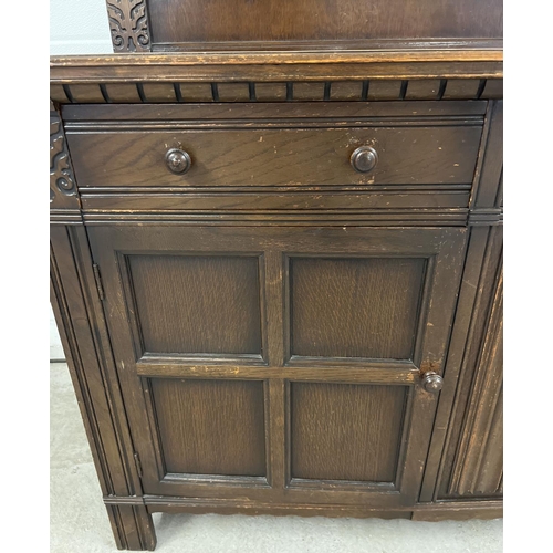 1398 - A vintage dark wood Old Charm style sideboard with carved detail and panelled doors. 2 cupboards to ... 