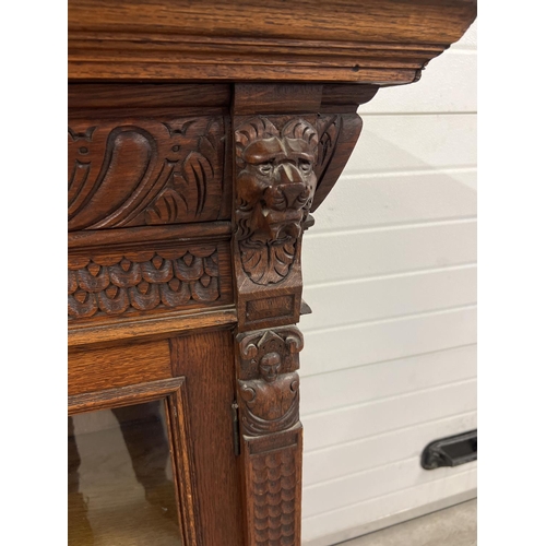 1399 - An antique dark wood wall hanging display cupboard with highly carved detail. With lion head finials... 