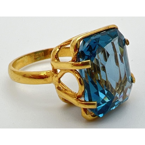 158 - An 18k gold cocktail ring set with a large emerald cut Swiss blue topaz stone. Claw setting with dec... 