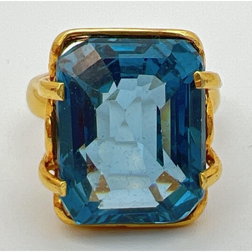 158 - An 18k gold cocktail ring set with a large emerald cut Swiss blue topaz stone. Claw setting with dec... 