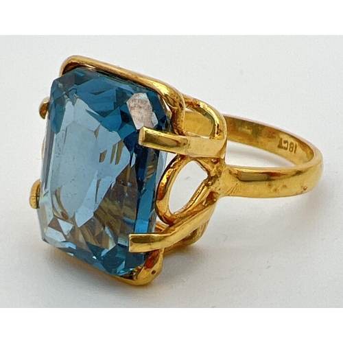 158 - An 18k gold cocktail ring set with a large emerald cut Swiss blue topaz stone. Claw setting with dec... 