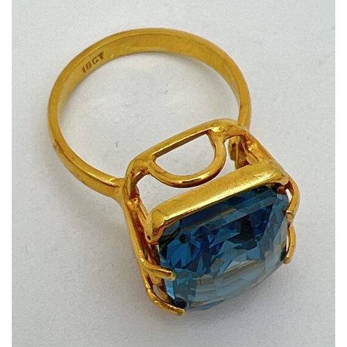 158 - An 18k gold cocktail ring set with a large emerald cut Swiss blue topaz stone. Claw setting with dec... 