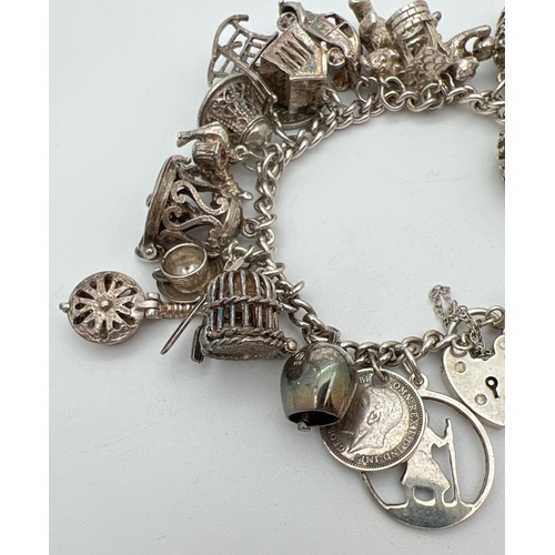 1004 - A vintage silver charm bracelet with padlock, safety chain and 27 silver and white metal charms. Man... 