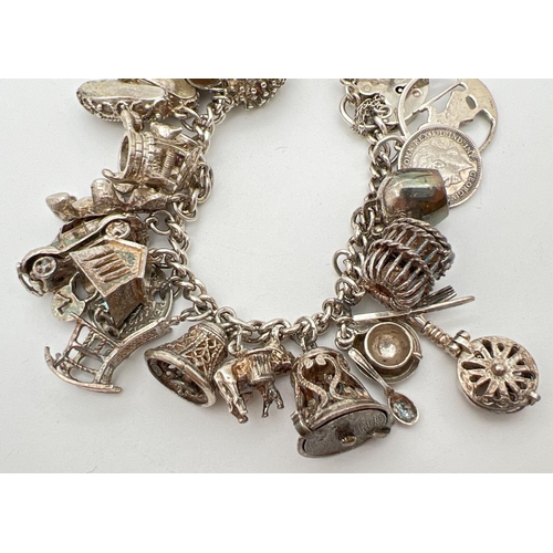 1004 - A vintage silver charm bracelet with padlock, safety chain and 27 silver and white metal charms. Man... 