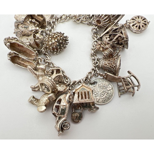 1004 - A vintage silver charm bracelet with padlock, safety chain and 27 silver and white metal charms. Man... 