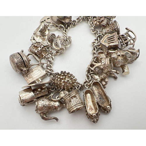 1004 - A vintage silver charm bracelet with padlock, safety chain and 27 silver and white metal charms. Man... 