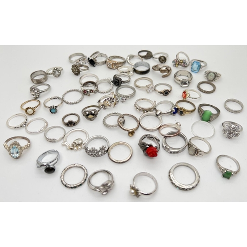 1019 - A collection of 60 assorted costume jewellery silver tone dress rings. In varying sizes and styles t... 