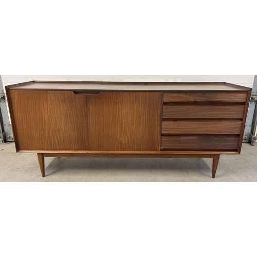 1387 - A mid century Afrormosia wood triple sideboard by Richard Hornby for Heals. Raised on tapered legs, ...