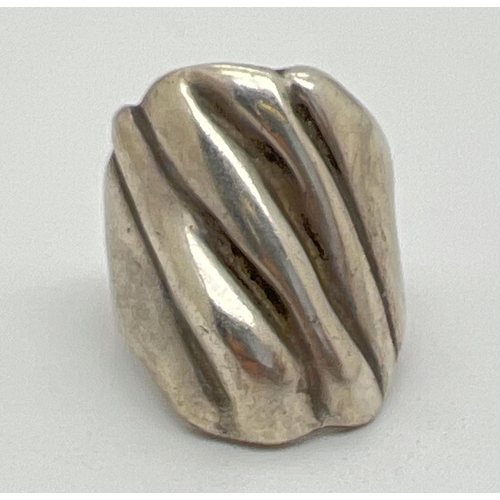 1051 - A contemporary design large silver dress ring. Rough grooved detail to top of ring. Worn 925 mark to... 