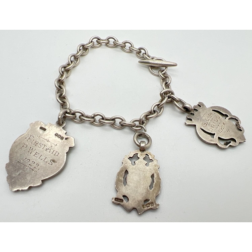 1056 - A vintage sterling silver charm bracelet with t bar style clasp and 3 silver shield medallions. Init... 