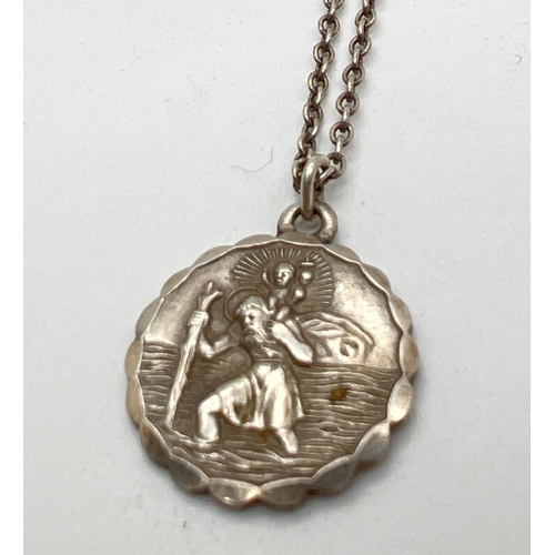 1064 - A vintage silver St. Christopher circular shaped pendant with Art Deco car and aircraft detail to ba... 