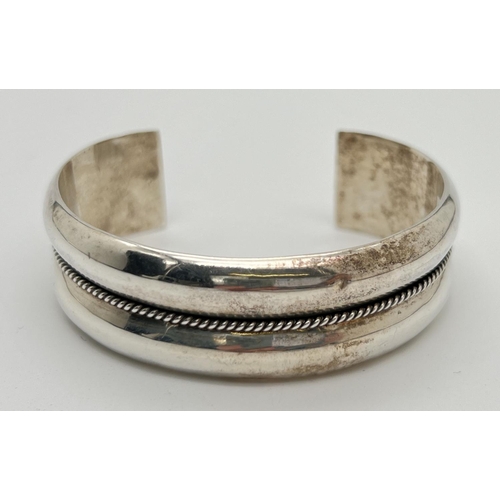 1065 - A 925 silver modern design cuff bangle with central rope style beading detail. Marked to inside of b... 