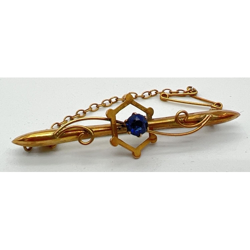 1072 - An Edwardian 9ct gold bar brooch with scroll decoration, safety chain and central blue glass stone. ... 