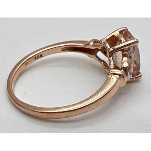 1083 - A 9ct rose gold, morganite and diamond dress ring. Central oval cut morganite with 2 small diamonds ... 