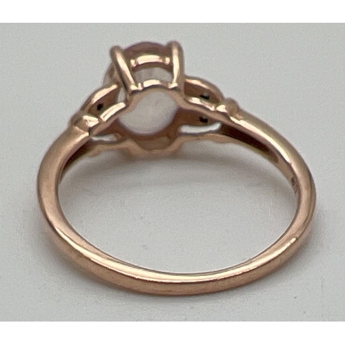 1083 - A 9ct rose gold, morganite and diamond dress ring. Central oval cut morganite with 2 small diamonds ... 