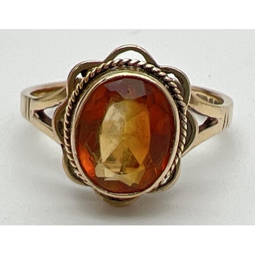 1086 - A 9ct gold citrine set dress ring. An oval cut citrine set in scallop edged mount with rope design d... 